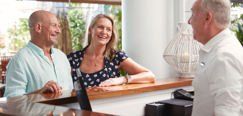 Three people conversing at a hotel reception desk.