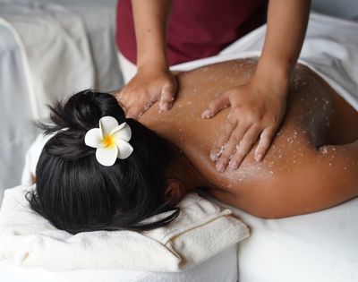 Person receiving a back massage with salt scrub at a spa.