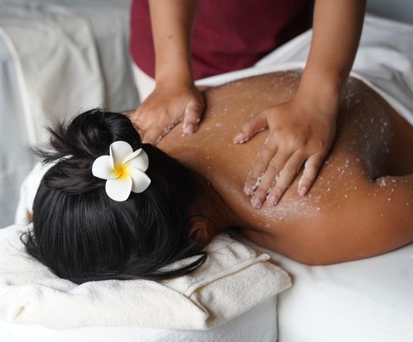 Person receiving a back massage with salt scrub at a spa.