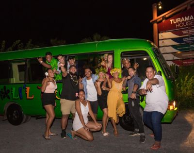 Group of people celebrating next to a green bus at night.