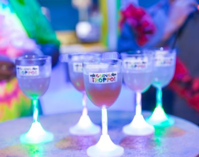 Glowing cocktail glasses on a table with blurred people in the background.