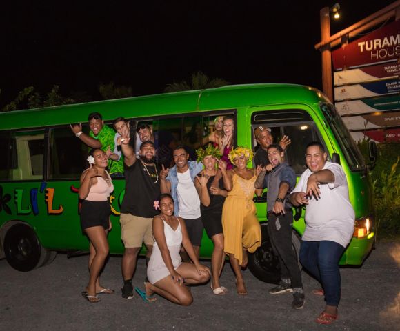 Group of people celebrating next to a green bus at night.