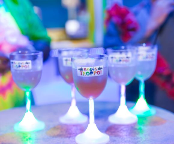 Glowing cocktail glasses on a table with blurred people in the background.