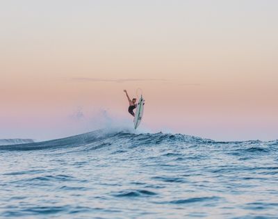 Surfer catching air on a wave at sunset.