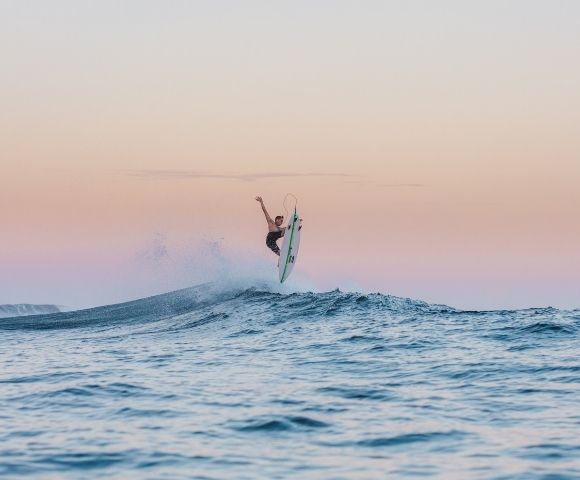 Surfer catching air on a wave at sunset.