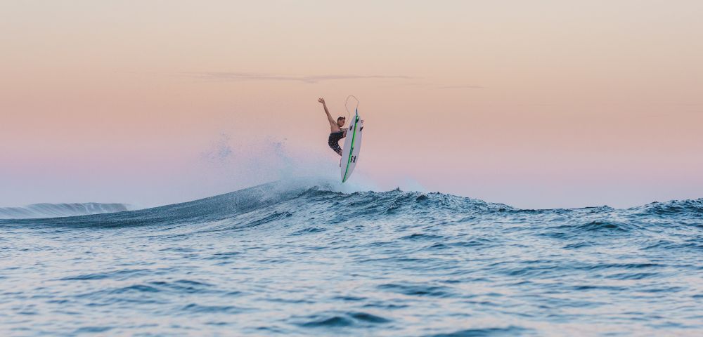 Surfer catching air on a wave at sunset.