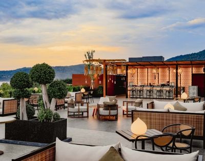 Rooftop patio with modern furniture overlooking a mountainous horizon at dusk.