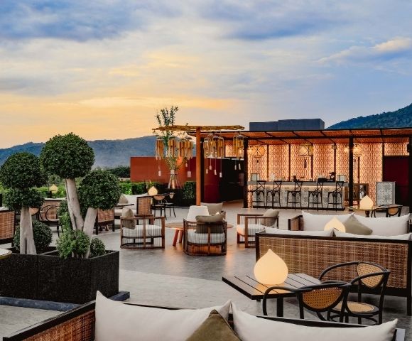 Rooftop patio with modern furniture overlooking a mountainous horizon at dusk.