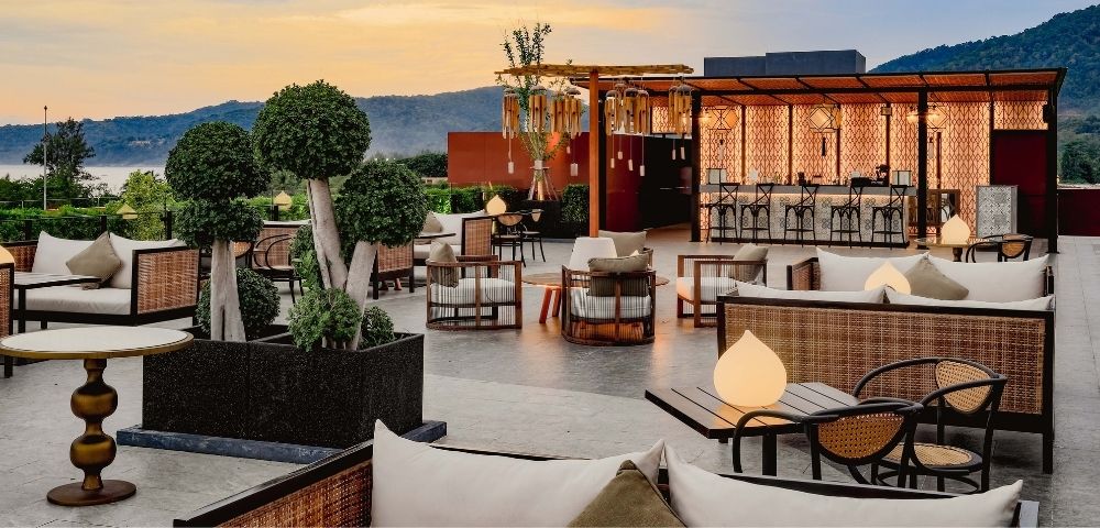Rooftop patio with modern furniture overlooking a mountainous horizon at dusk.