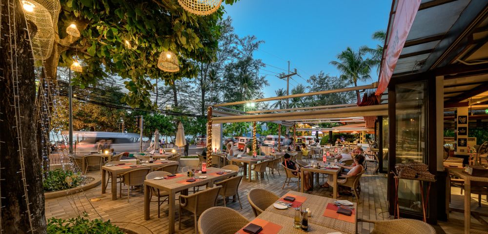 Outdoor restaurant patio with tables set for dining, string lights, and evening ambiance.