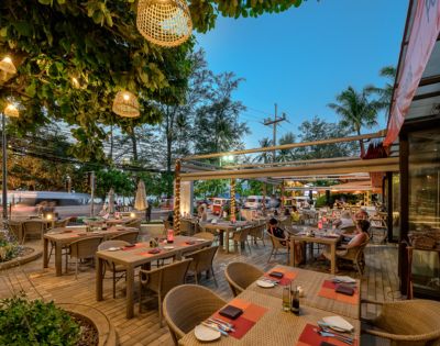 Outdoor restaurant patio with tables set for dining, string lights, and evening ambiance.