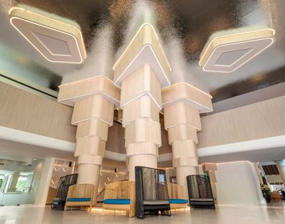 Modern hotel lobby with unique geometric ceiling design and stylish seating areas.