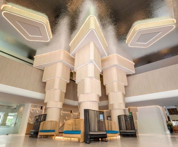 Modern hotel lobby with unique geometric ceiling design and stylish seating areas.