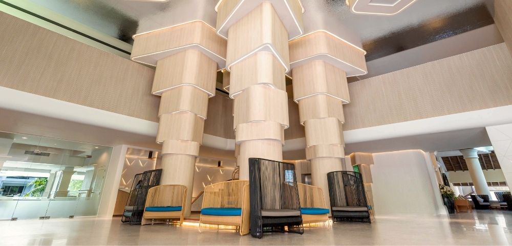 Modern hotel lobby with unique geometric ceiling design and stylish seating areas.