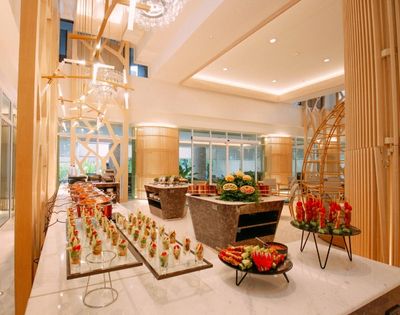 Elegant hotel lobby with a buffet setup and modern chandeliers.
