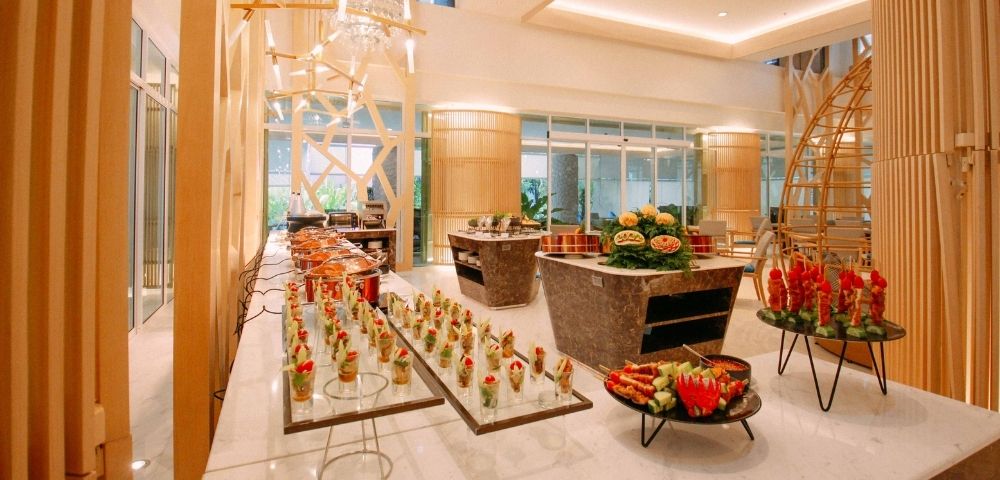 Elegant hotel lobby with a buffet setup and modern chandeliers.