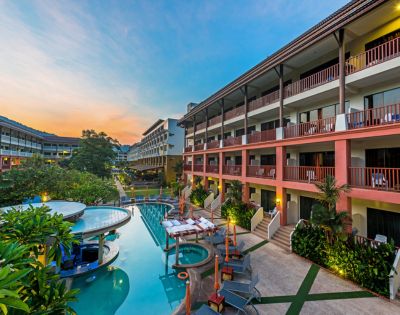 Resort with pool at sunset, surrounded by multi-story buildings.