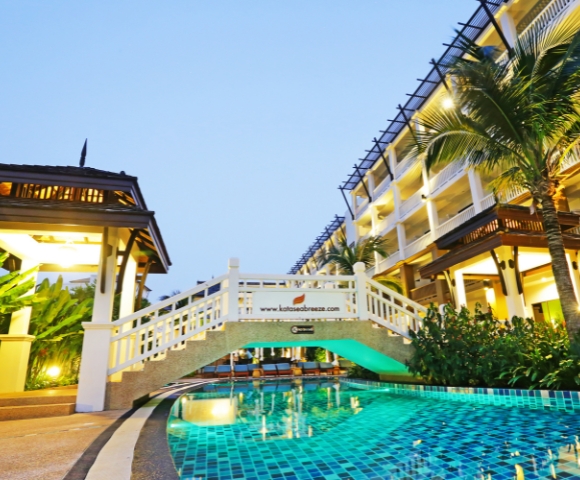 Luxury hotel with a bridge over a pool at twilight.
