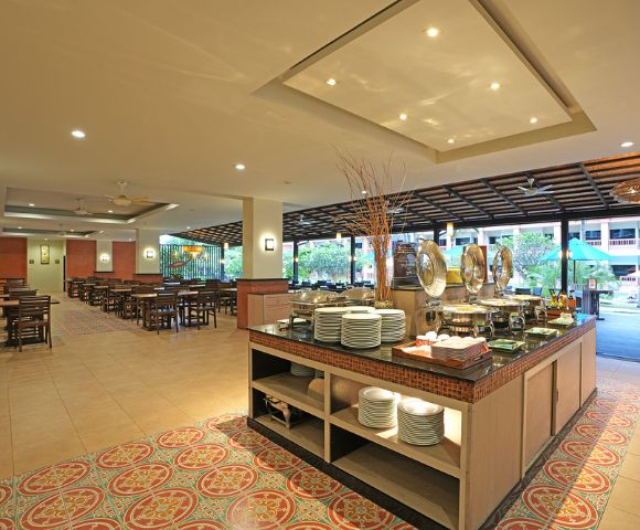 Spacious hotel buffet area with serving counters and seating arrangement, decorated with warm lighting.