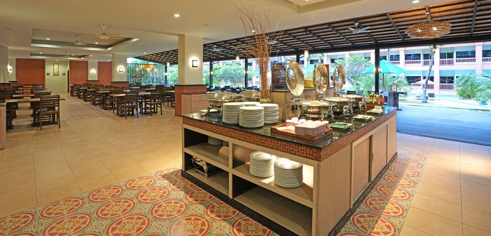Spacious hotel buffet area with serving counters and seating arrangement, decorated with warm lighting.