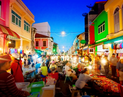 A vibrant night market bustling with people, colorful stalls, and bright lights illuminating the lively street scene.