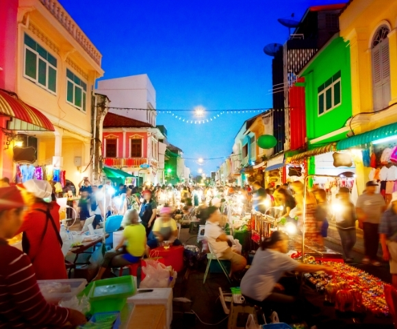 A vibrant night market bustling with people, colorful stalls, and bright lights illuminating the lively street scene.