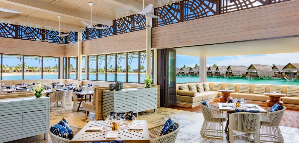 Bright, modern restaurant with elegant decor, large windows overlooking a serene water view, and cozy seating areas.