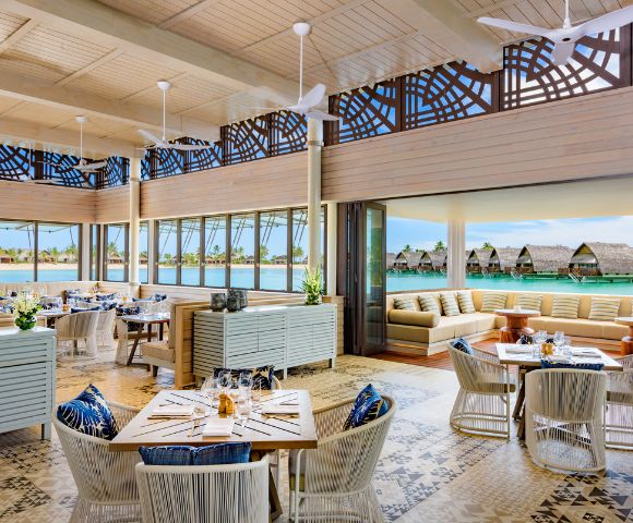 Bright, modern restaurant with elegant decor, large windows overlooking a serene water view, and cozy seating areas.