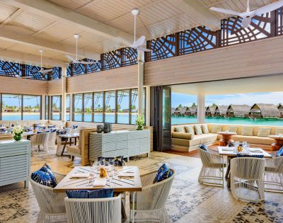 Bright, modern restaurant with elegant decor, large windows overlooking a serene water view, and cozy seating areas.