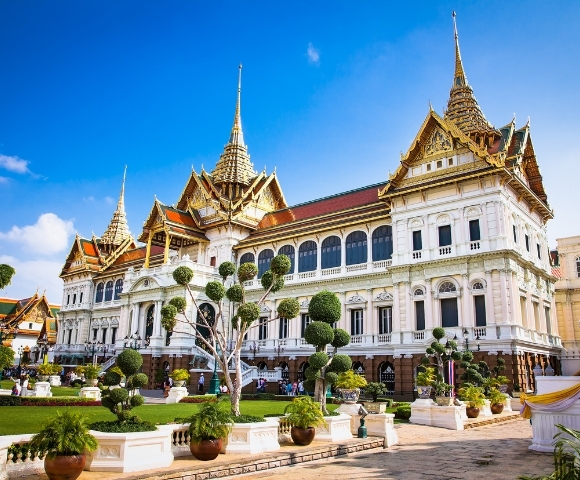 The Grand Palace in Bangkok, showcasing intricate architecture and lush gardens under a clear blue sky.