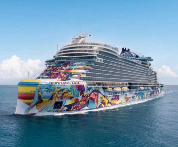 The Norwegian Aqua cruise ship, adorned with vibrant murals, sails on calm blue waters under a bright sky.