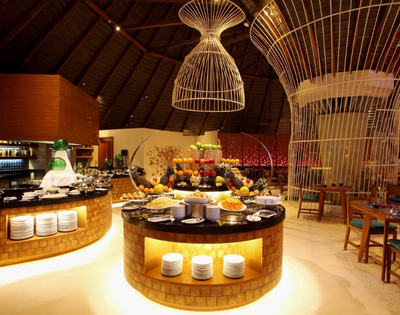 A chic restaurant interior featuring elegantly arranged food displays, colorful fruit, and a striking modern decor with high ceilings.