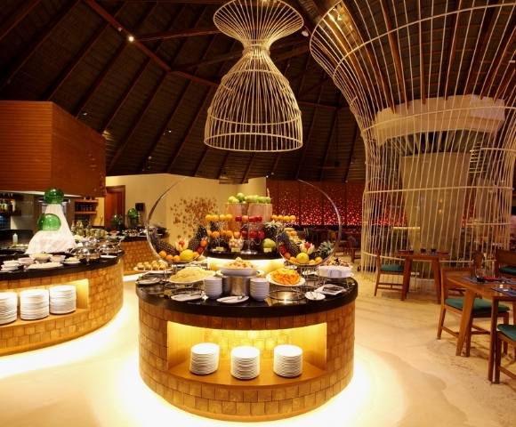 A chic restaurant interior featuring elegantly arranged food displays, colorful fruit, and a striking modern decor with high ceilings.