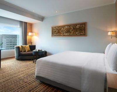 Modern hotel room featuring a king-sized bed, seating area, large window, and decorative wall art.