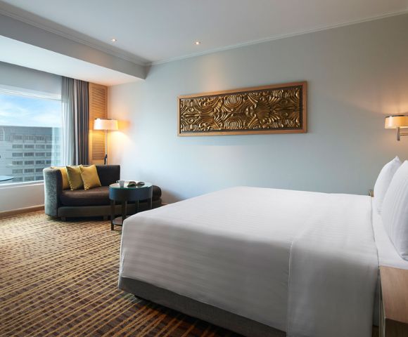 Modern hotel room featuring a king-sized bed, seating area, large window, and decorative wall art.