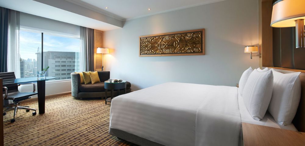 Modern hotel room featuring a king-sized bed, seating area, large window, and decorative wall art.