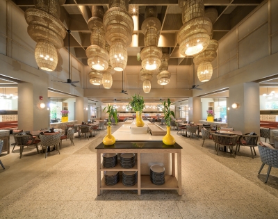 Bright, modern restaurant interior with woven pendant lights, a central table with vases, and cozy seating arranged in an inviting layout.