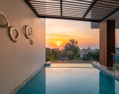 Sunset view from a luxurious poolside, with modern artwork on the wall and a serene landscape beyond.