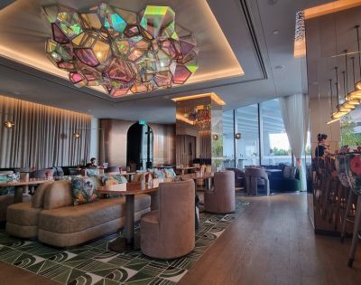 Elegant restaurant interior featuring modern decor, colorful seating, and a striking geometric chandelier above.