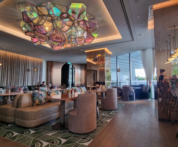 Elegant restaurant interior featuring modern decor, colorful seating, and a striking geometric chandelier above.