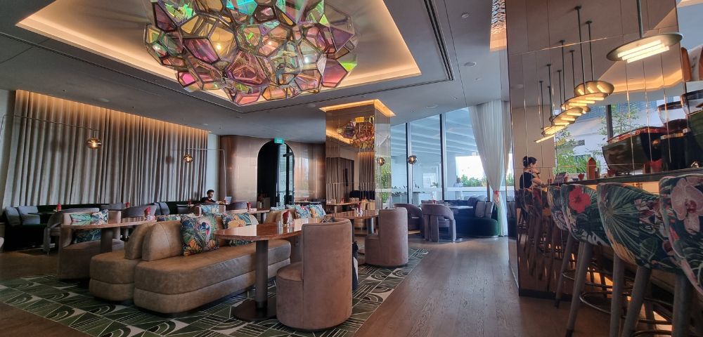 Elegant restaurant interior featuring modern decor, colorful seating, and a striking geometric chandelier above.