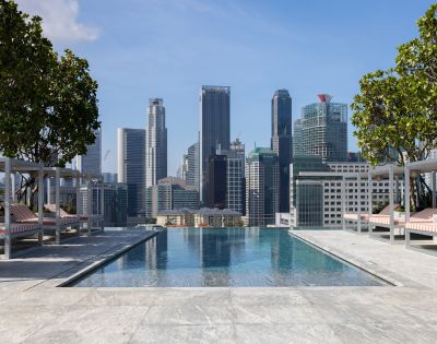 Rooftop infinity pool overlooking a vibrant city skyline, with lounge chairs and greenery adding to the luxurious ambiance.