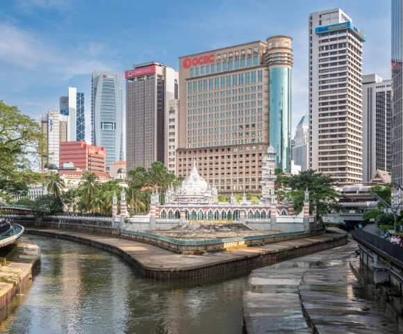 A vibrant cityscape featuring historic architecture alongside modern skyscrapers, with a river winding through the urban landscape.