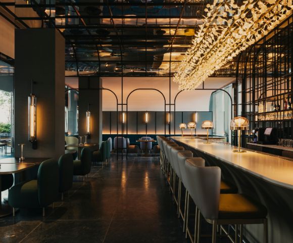 Stylish restaurant interior featuring a long bar with elegant lighting, modern seating, and a contemporary design atmosphere.