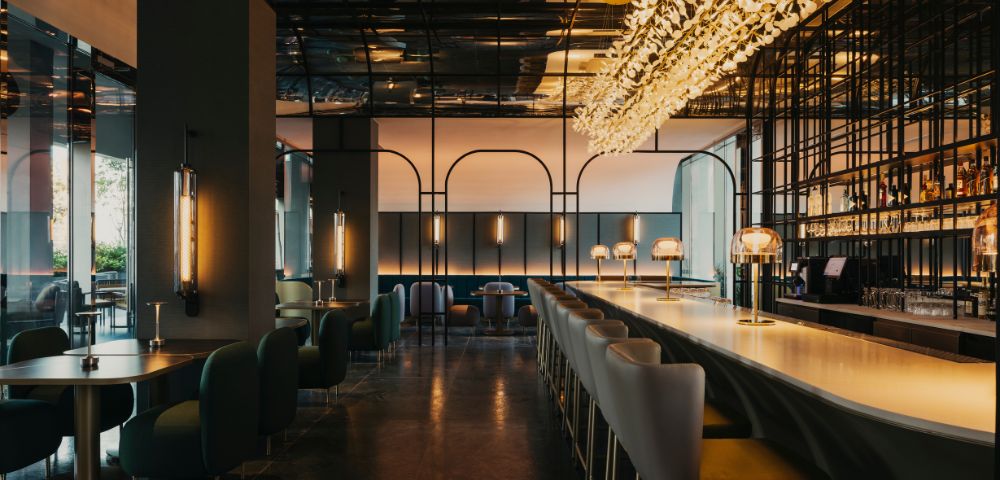 Stylish restaurant interior featuring a long bar with elegant lighting, modern seating, and a contemporary design atmosphere.