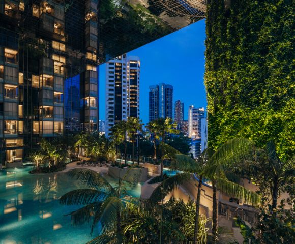 Luxurious urban oasis with a serene pool surrounded by lush greenery, reflecting modern skyscrapers under a twilight sky.