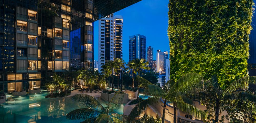 Luxurious urban oasis with a serene pool surrounded by lush greenery, reflecting modern skyscrapers under a twilight sky.