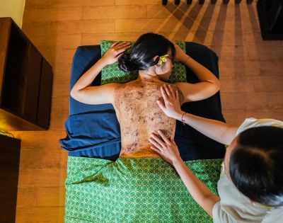 A woman receiving a back massage in a serene spa setting, surrounded by calming decor and soft lighting.