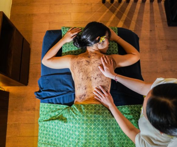 A woman receiving a back massage in a serene spa setting, surrounded by calming decor and soft lighting.