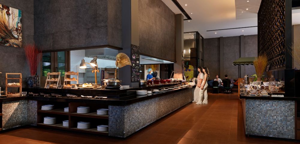 Modern restaurant interior featuring a buffet with diverse dishes, sleek decor, and diners enjoying a meal in a stylish ambiance.